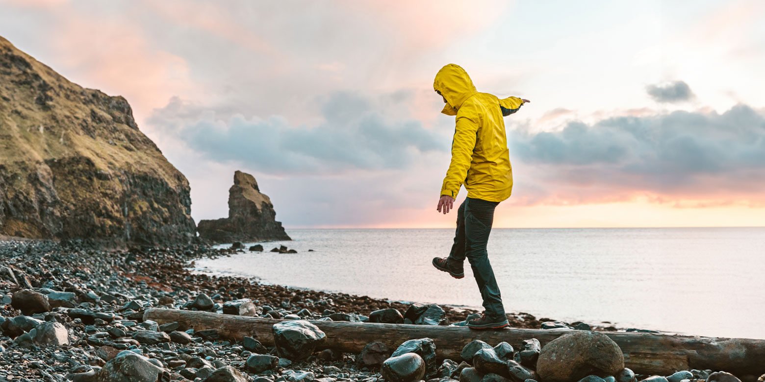 Person on the shoreline balancing on a log