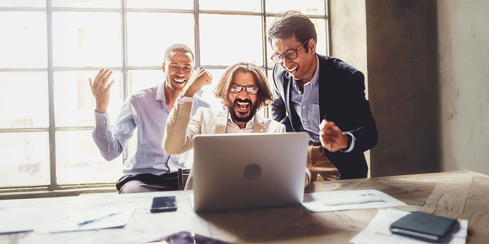 Three men cheering looking at a computer screen