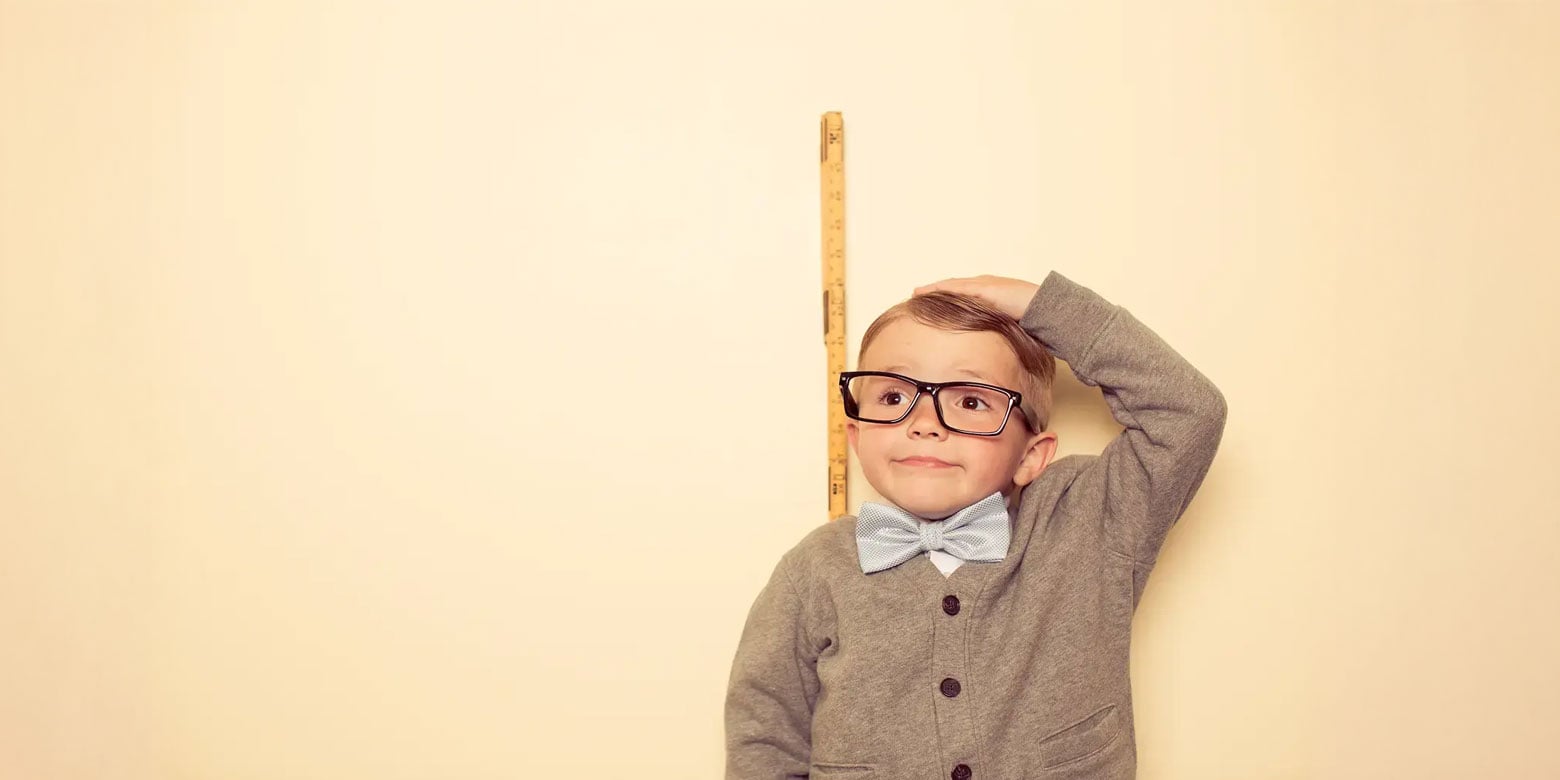 Small child measuring himself against a wall