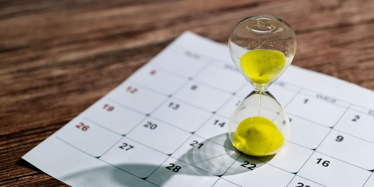 An hourglass on top of a calendar