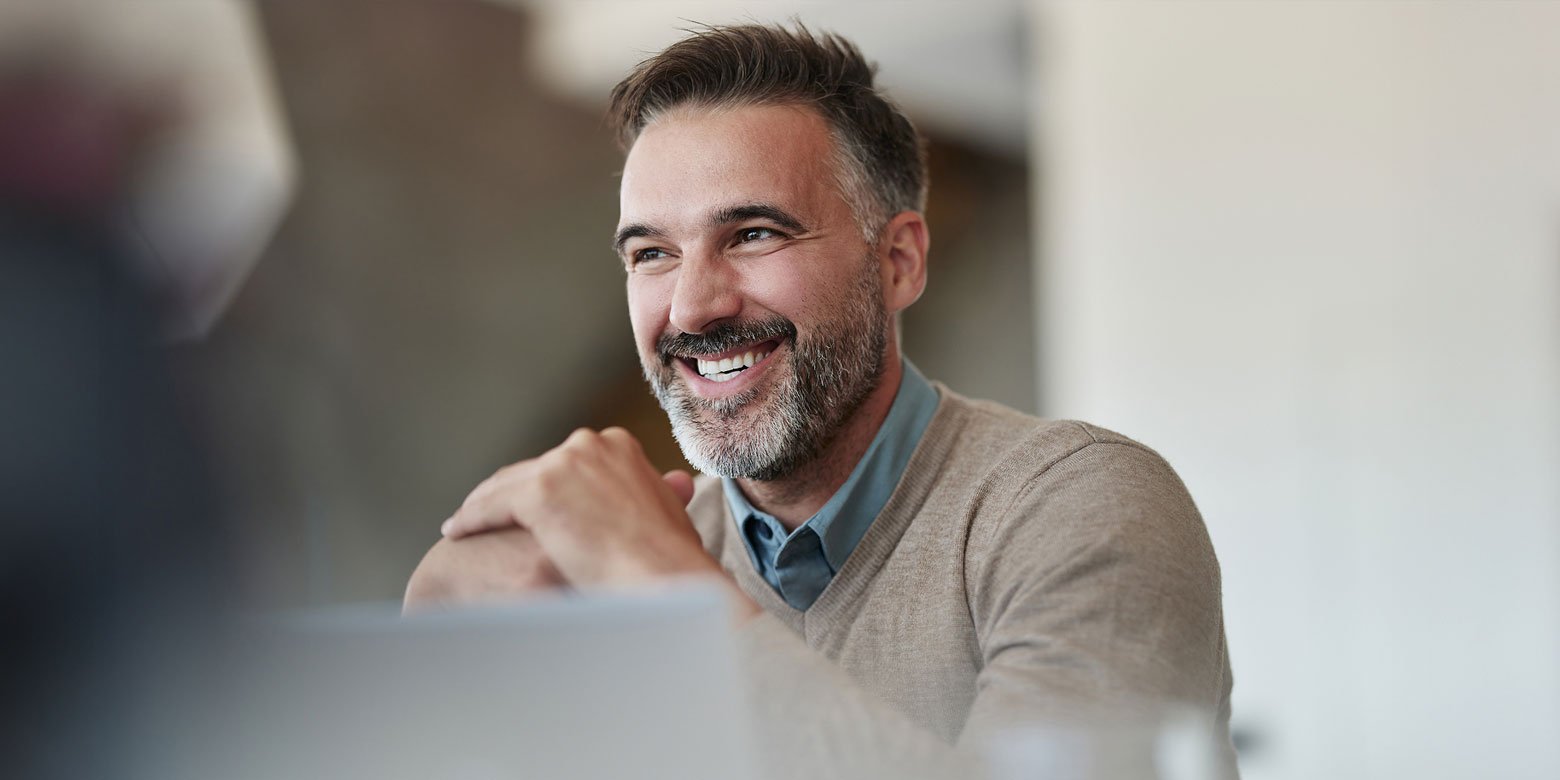 Man smiling behind a laptop